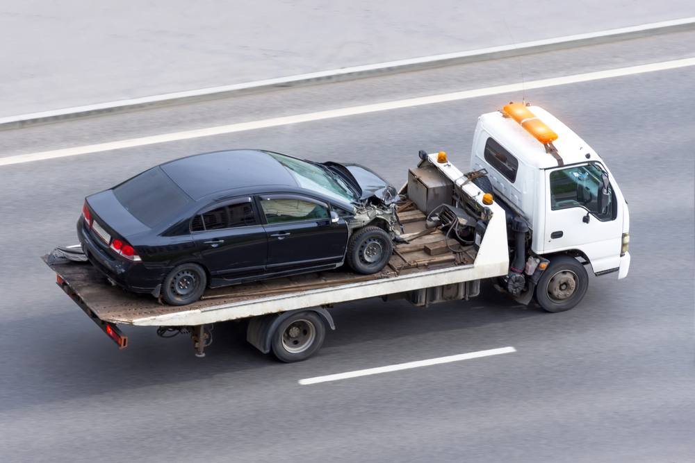 Wrecked car loaded on a flatbed tow truck