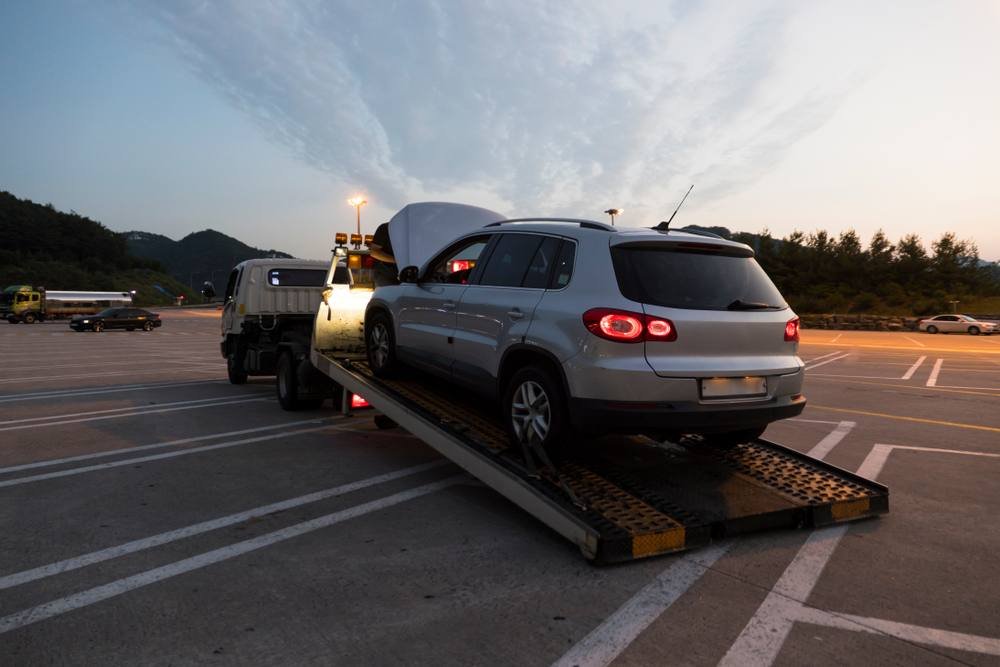 Silver SUV being loaded onto a flatbed tow truck