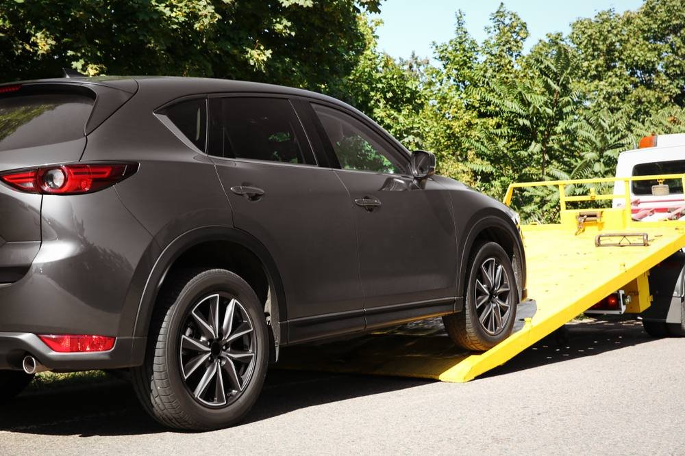 Black SUV being winched onto a flatbed tow truck