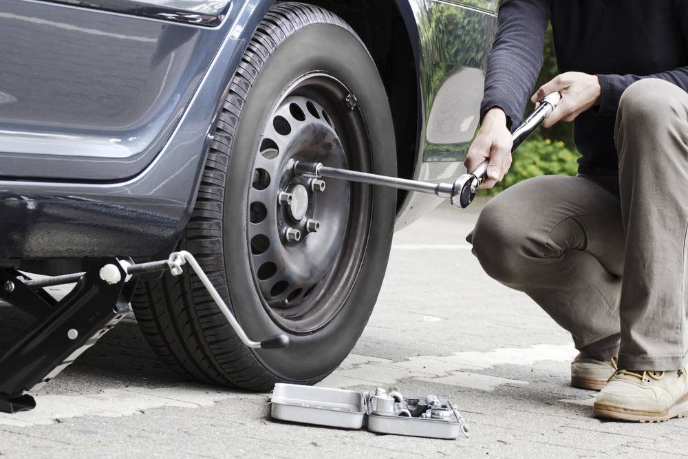 Man changing a flat tire at the side of the road