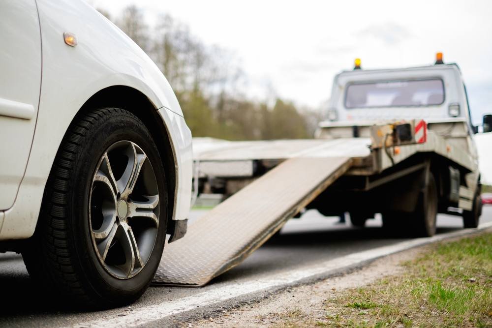 White car being pulled onto a flatbed tow truck